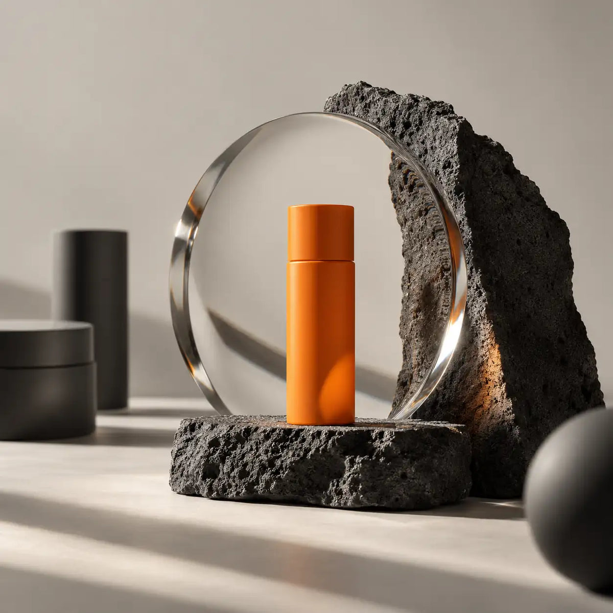 Orange produktflaska sedd genom en glasskiva på en mörk stensockel